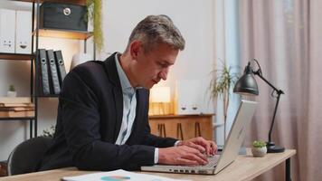 Bored Caucasian young businessman sitting with laptop computer while sleeping at home office desk video