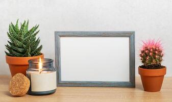 Empty frame, burning candle and succulents creating cozy home atmosphere photo