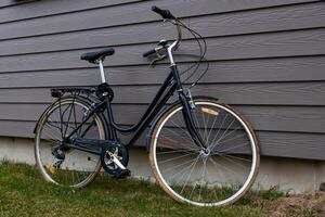 Black Bicycle with Step Through Frame by Gray Wooden House Wall photo