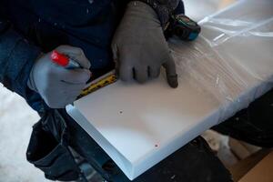 Worker Measuring White Panel with Red Marker and Measuring Tape photo