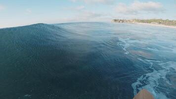 Surfer rides on ocean wave at Balangan surf spot in Bali island, action camera first person view video