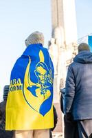 Person with Ukraine Flag Near Freedom Monument in Riga, Latvia photo