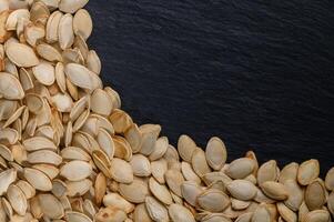 Harvesting the bounty of nature with dried pumpkin seeds on a rustic slate background photo