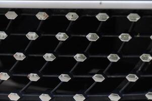 Close-up view of an intricate car grille design showcasing geometric patterns and textures in a modern aesthetic photo