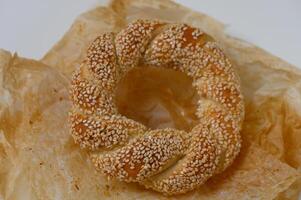 Freshly baked sesame bread ring rests on parchment paper, showcasing its golden brown crust and delicate texture, ready to be enjoyed photo