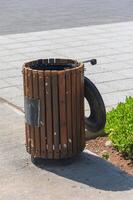 Creative trash bin design combines wood and tire for an artistic urban element in a bustling cityscape photo