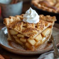 Warm apple pie slice topped with creamy whipped cream served on a rustic plate. photo