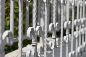 Curved white iron railing details spark imagination with intricate design elements in a sunlit garden setting photo
