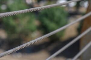Close-up of steel cables highlighting texture amidst blurred natural background during a sunny day in a park setting photo