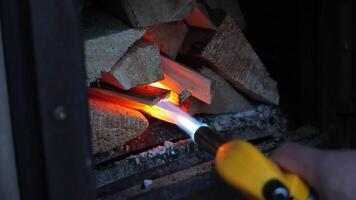 Igniting firewood with gas torch inside fireplace using kindling technique video