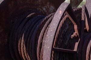 Rusty cable reel resting in the sunlight with a backdrop of serene nature on a clear afternoon photo