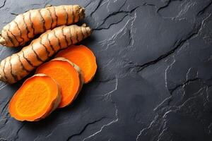 Fresh and Sliced Turmeric Root on Dark Marble Surface for Culinary and Health Concepts photo