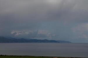 Skies over a tranquil coastal landscape capture the essence of a serene afternoon with dramatic clouds and still waters reflecting nature's beauty photo