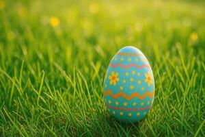 A blue Easter egg with bright patterns lies in the fresh green grass, symbolizing the joy of spring and the festive atmosphere. photo