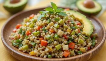 There is a delicious couscous dish on a wooden plate, decorated with cubes of bright vegetables, herbs and slices of avocado. The marble-topped table complements the fresh and healthy look of photo