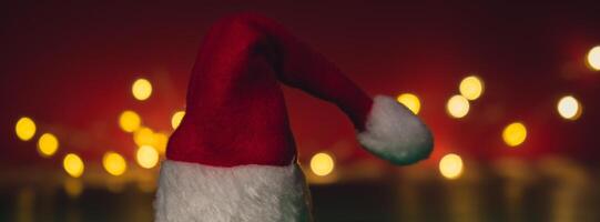 Santa hat on isometric green red background. Defocused lights on backdrop Copy space for your text. Mock up for advertisement. Holiday Christmas composition. Minimalistic greeting card. Creative photo