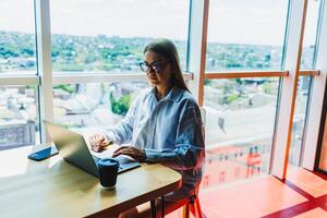 A woman is currently seated at a table while using a laptop computer photo