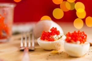 Festive snacks. boiled eggs with red caviar on a blurred New Year's background. photo
