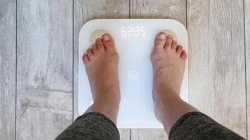 A person stands on a digital scale, revealing a measurement of 62.35 kg, suggesting a moment of self-reflection or weight tracking. photo