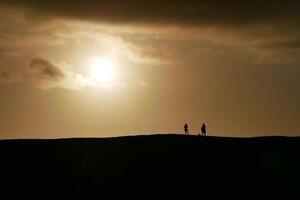 People watching a colorful sunset in a Maspalomas dune, Gran Canaria island photo