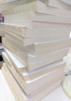 A stack of white paper books sitting on top of a table photo