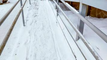 Close-up of a ramp with metal railings, covered with snow, for baby strollers and handicapped accessibility photo