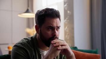 Anxious tired sad Caucasian business man male guy businessman depressed troubled homeowner bearded client sitting sofa folded hands arms holding head trouble health problem difficulty bankrupt at home video