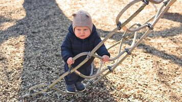 One year old boy in a black jacket runs and plays outside on the playground. Child learns the world video