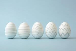 Elegant pastel Easter eggs with delicate silver line patterns arranged on a soft blue background, showcasing a minimalist and modern design. photo