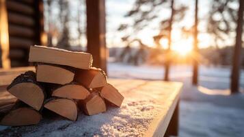 Firewood covered a snow on a wooden table in front during beautiful log cabin landscape sunset in a with winter of photo