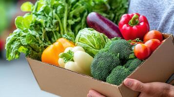 Farmer carrying cardboard box brimming with freshly harvested organic vegetables from local farm fields photo