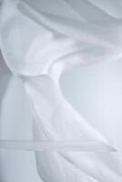 Empty glass shelf with flowing white cloth backdrop creating a soft, elegant setting, ideal for showcasing products or creating a minimalist aesthetic photo