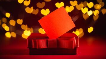 Red gift box adorned with a ribbon sits against a backdrop of glowing heart-shaped bokeh lights, evoking a romantic and festive valentine's day atmosphere photo