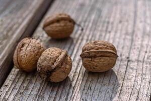 Closeup of four whole walnuts on aged wooden surface with natural textures and warm tones. Organic food, natural patterns, textures, and healthy nutrition. Copy space. Selective focus 02 photo