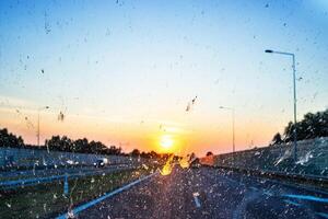 Highway view at sunset through a dirty windshield, emphasizing road safety and the challenges of visibility while driving on long journeys. Transportation, logistics, road traffic. Copy space 03 photo