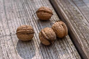Closeup of four whole walnuts on aged wooden surface with natural textures and warm tones. Organic food, natural patterns, textures, and healthy nutrition. Copy space. Selective focus 01 photo
