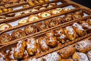 Assortment of freshly baked pastries topped with icing, coconut flakes, and powdered sugar displayed in woven baskets displayed in rustic woven wicker baskets on the shelf of grocery store 01 photo