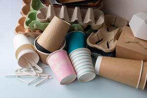 Paper cups with lids and egg cartons are piled on the table photo