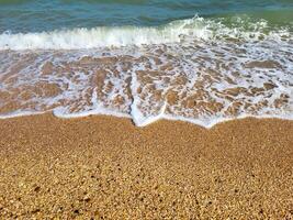 The concept of recreation. Beautiful azure sea with white foam and a beach on a clear sunny day photo