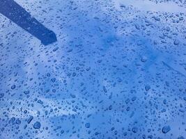 Raindrops and reflections on the blue metal surface of the hood on a summer day photo