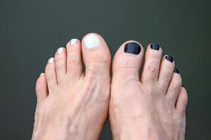 Bare feet with black and white painted toenails resting near a body of water. Two feet with contrasting nail polish, symbolizing individuality, personal style and relaxation. Copy space 02 photo