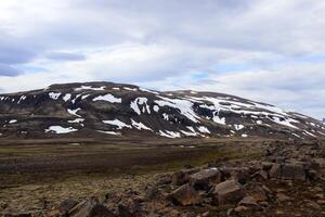 Snowy Icelandic mountain partially covered by snow during summer photo