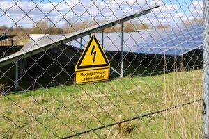 High voltage sign protecting solar panels behind fence photo