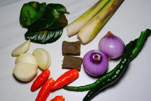 Food Ingredients for making sambal. Isolated Spices consisting of chili, onion, shrimp paste, lemongrass and lime leaves on white background. Copy space. Raw Ingredients for Indonesian Sambal photo