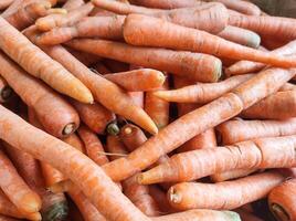 Group of fresh carrots stacked. Vegetable Backgrounds sold in traditional market shelf. Orange and tiny carrot. Texture and details. Vegetable themes wallpaper. Organic carrots background photo