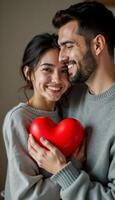Couple holding red heart shaped object close, demonstrating affection and joy photo