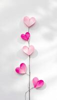 Five paper hearts on a branch against a white background with shadows and copy space photo