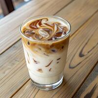 Iced Coffee Drink with Swirled Caramel in Glass on Wood Table Top View photo