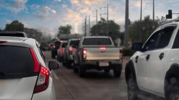 Traffic jam on the concrete road after rainy. Rear side of white car with turn on brake light. On car boy with drop of water rain. Many car in parked in a double row of tires. Environment in evening. photo
