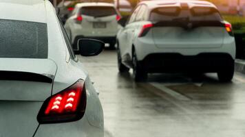 Rear side of white car on the car with wet from water rain. Turn on brake signal on the wet concrete road. Many car queue and stop on the road by trffic condition. photo